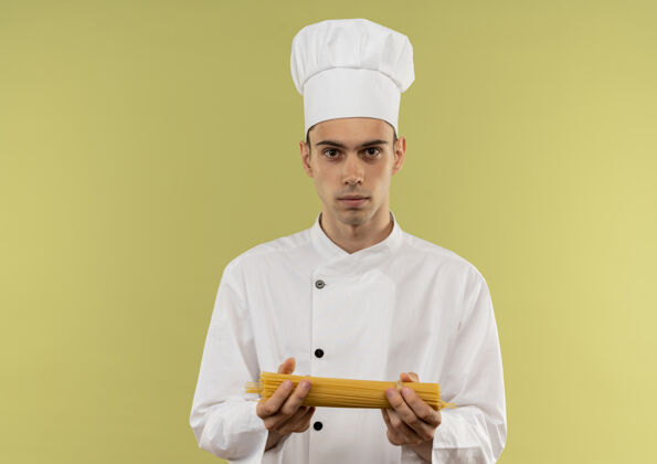 厨师身穿厨师制服的年轻男厨师在与世隔绝的绿墙上举着意大利面意大利面戴着男