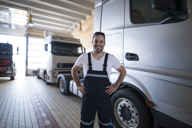 制服正面微笑的卡车维修工站在车间卡车旁的画像机械师检查扫描