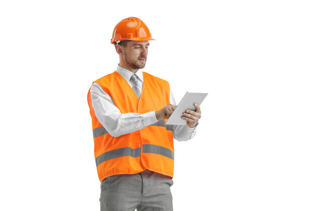 男人一个穿着建筑背心 戴着带石碑的橙色头盔的建筑工人男人项目工业