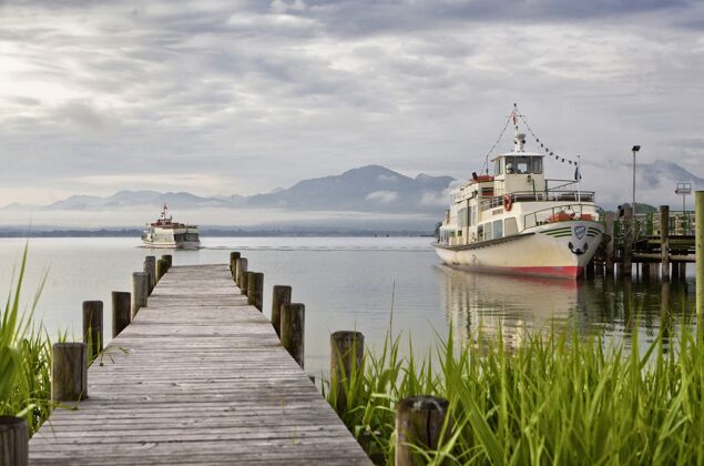 海滩美丽的木质甲板通向大海 山和船的背景休闲码头木制