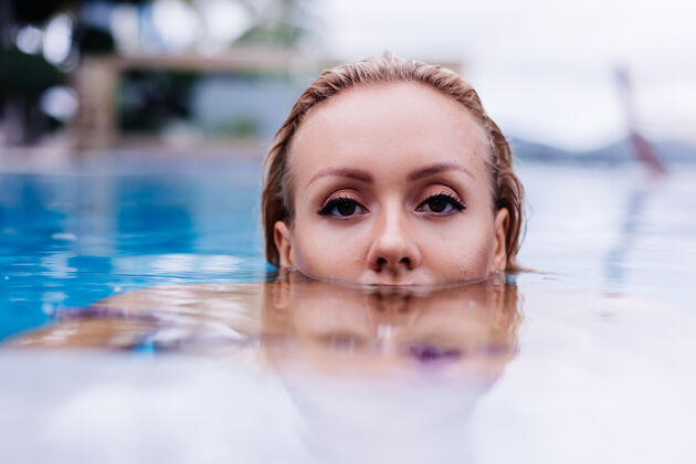 休闲穿着比基尼的白种女人在蓝色游泳池的时尚写真 在coudydaynaturallight度假户外放松女士