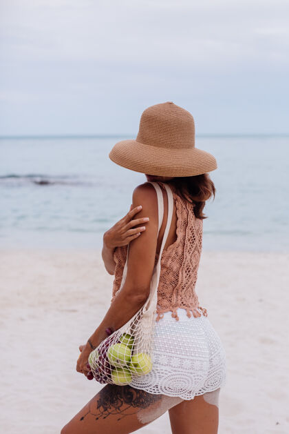 女士年轻漂亮的白种人 皮肤黝黑 穿着针织衣服 戴着帽子在沙滩上成人微笑帽子