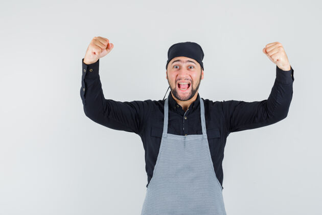 餐厅男厨师在衬衫 围裙上展示成功的姿态 看起来很幸福 正面视图美食人厨师