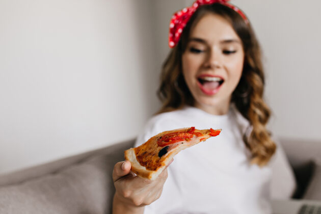 快乐快乐的年轻女子看着披萨片的模糊照片有趣放松的女孩在家里享受快餐的室内照片人饮食美丽
