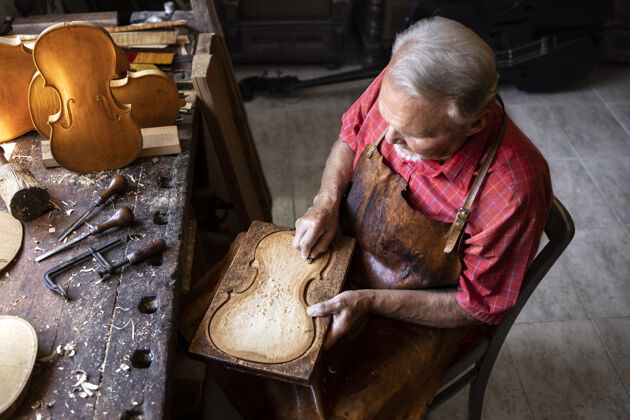 勤劳高级木匠在旧时装工作室工作的顶视图手册工匠制作