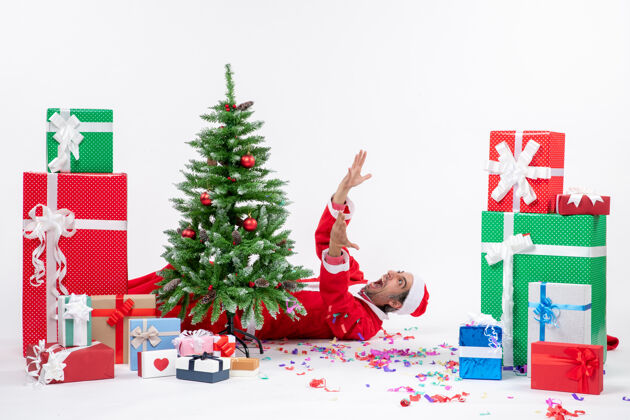 圣诞树圣诞老人躺在圣诞树后面 靠近白色背景上的礼物节日年轻礼物