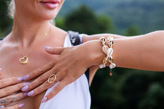 配件戴着戒指和手镯的女士手的近景照片有吸引力贝壳自然