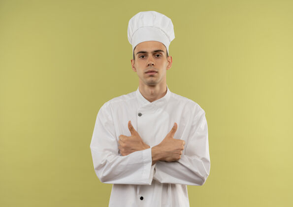 拇指自信的年轻男厨师穿着厨师制服 双手竖起大拇指 站在隔离的绿色墙壁上 留着复印空间穿着厨师手
