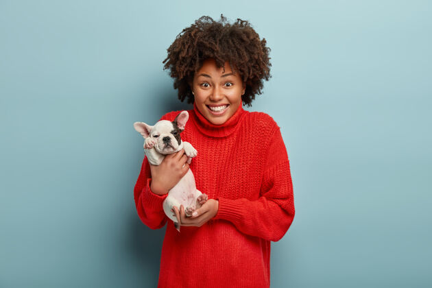 黑发非洲裔美国妇女穿着红色毛衣牵着狗动物成人肖像