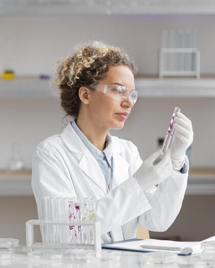 实验室实验室里的女研究员拿着试管和安全眼镜技术生物学试管